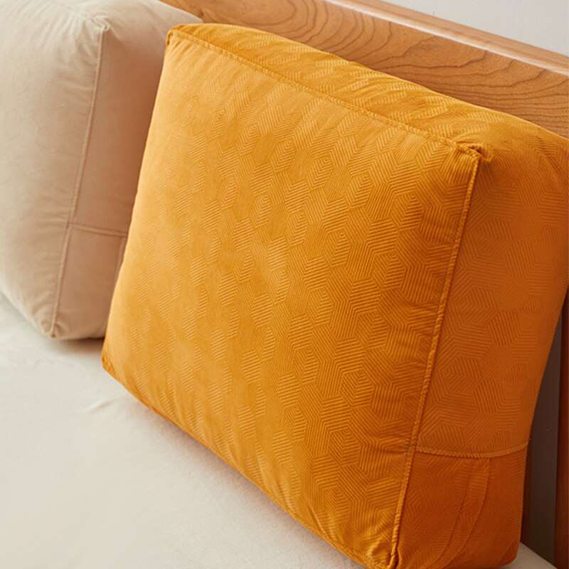 a brown and orange pillow sitting on a bed 